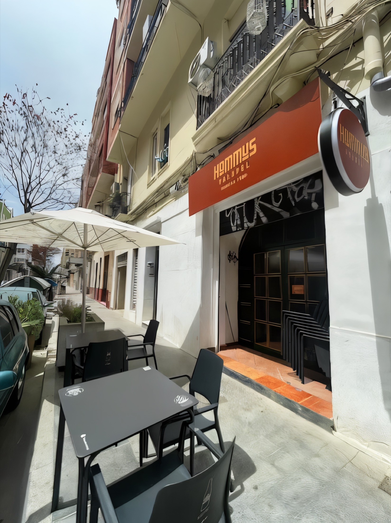 Hommus Falafel storefront with its terracotta awning and terrace